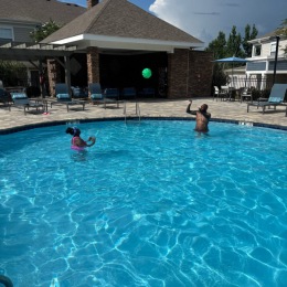 people playing in a pool with lounge chairs around it